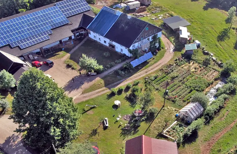Man sieht eine Luftaufnahme eines Bauernhofs und den umliegenden landwirtschafltlichen Flächen.